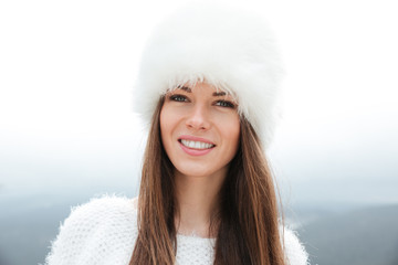 Pretty woman wearing white hat standing over mountains