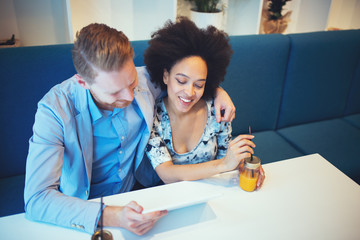 Obraz premium Multiracial couple dating. Handsome redhead man with beautiful Afro american woman having some good time in cafe bar or restaurant.