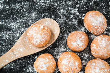 Soft, delicious fresh doughnuts sprinkled with powdered sugar on the black background. Christmas time. Homemade pastries.