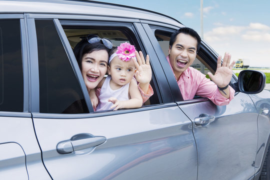 Cheerful Family Waving Hands In The Car