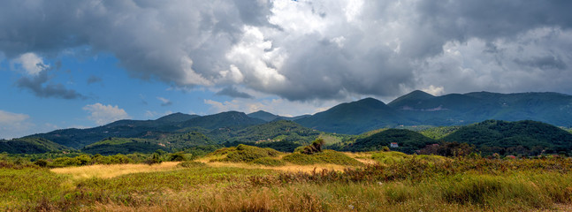 Dramatic clouds over the fields and mountains near the beach in Acharavi village. Corfu island,...