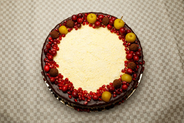 Triple chocolate cake decorated with pomegranate, cranberries and small apples.
