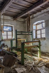Damaged vintage weaving machine in an old abandoned house with grunge wall and wooden ceiling.