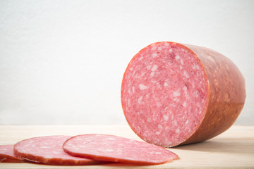 Smoke-dried sausage with slices on the wooden board in the kitchen.