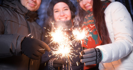 Friends celebrating Christmas lighting sparklers