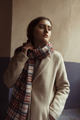 Fashionable brunette model  in scarf posing in the passage