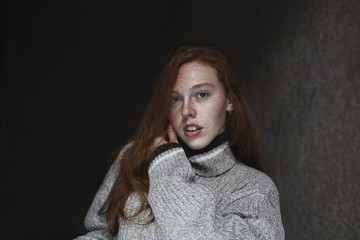 Sensual young model with freckles posing in the dark room