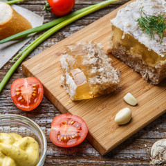 Homemade jelly meat with mustard, bread, tomatoes and garlic on the table. Holodets