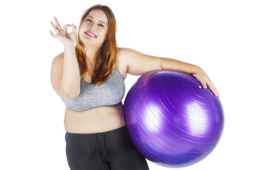Obese female showing ok sign with fitness ball