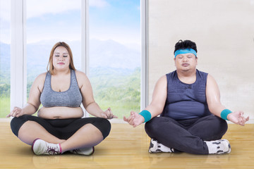 Obese group people meditating indoors