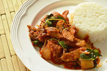 spicy stir fried roasted pork curry with herb eat couple with rice on plate