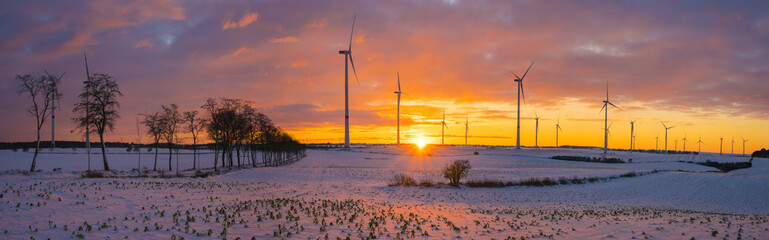 windmills (wind turbines) on the snow-covered field at sunset