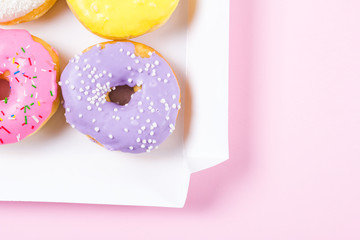 Six colorful round donuts in the box. Flat lay, top view.