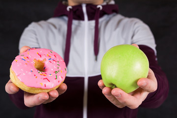 Man offering apple and donut as concept of healty lifestyle