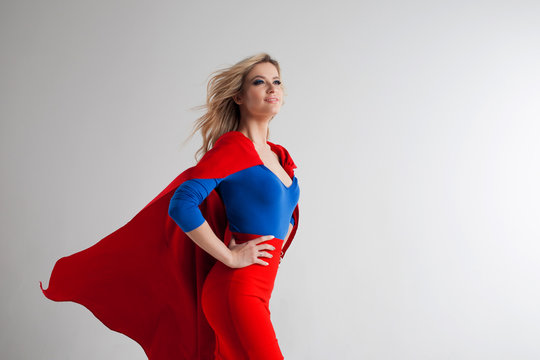 Superhero Woman. Young and beautiful blonde in image of superheroine in red Cape growing