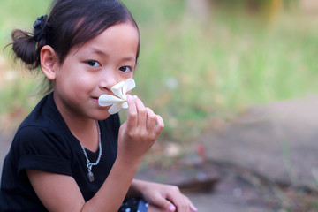 Little girl smelling the Plumeria flower.