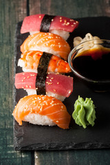 Sashimi and sushi rolls on a stone slatter. Sushi set with salmon, prawns, soy souce, wasabi and ginger. Traditional Japanese cuisine.