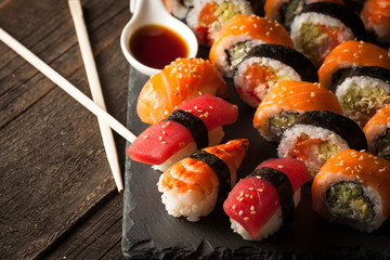 Sashimi and sushi rolls on a stone slatter. Sushi set with salmon, prawns, soy souce, wasabi and ginger. Traditional Japanese cuisine.