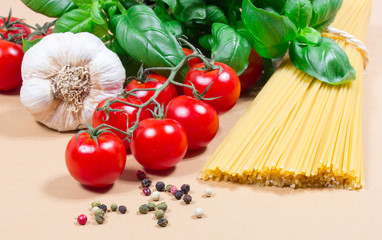Raw pasta and ingredients for pasta with tomatoes and basil.