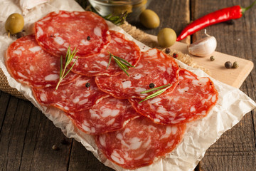 Chorizo sausage and salami, thin cut. spanish salami on the wood background with spices, paprika, pepper. Spicy food. Chili.