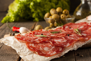 Chorizo sausage and salami, thin cut. spanish salami on the wood background with spices, paprika, pepper. Spicy food. Chili.