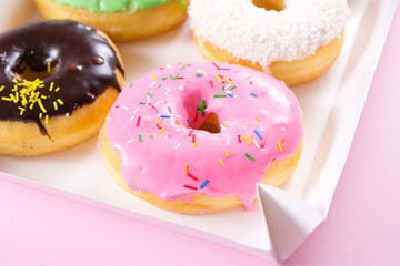 Strawberry, chocklate and other donuts in paper box on pink background