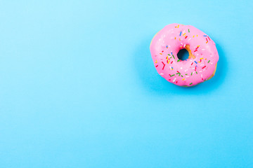 Pink round donut on blue background. Flat lay, top view.