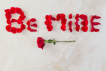 rose petal note/Word "Be Mine" made of rose petal and a rose on the marble table. 