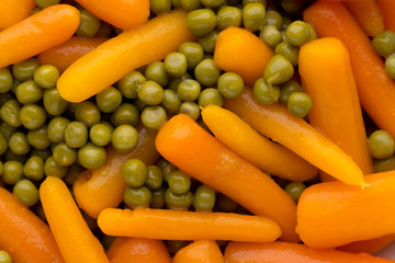Carrots with green peas vegetable background.