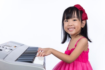 Happy Asian Chinese little girl playing electric piano keyboard