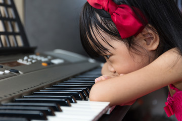 Boring Asian Chinese little girl playing electric piano keyboard