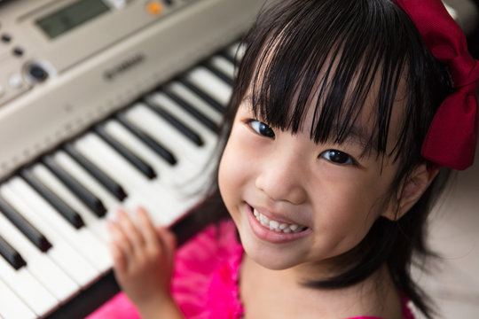 Happy Asian Chinese Little Girl Playing Electric Piano Keyboard