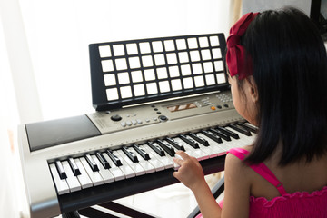 Asian Chinese little girl playing electric piano keyboard