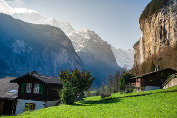 Fototapeta na wymiar Green fields in Lauterbrunnen valley with the waterfall and the Alps in the background, Berner Oberland, Switzerland - April, 2016