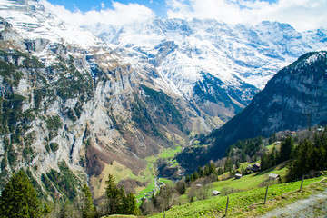 The Snow-covered Swiss Alps in background and Green field at Murren Village, Jungfrau region, Switzerland - April, 2016