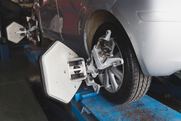 Fototapeta premium Car wheel fixed with computerized wheel alignment machine clamp