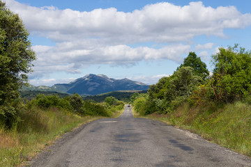Fototapeta na wymiar Carretera Secundaria en Paisaje Montañoso con coche a lo lejos