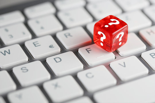 Rot farbener / roter W&uuml;rfel mit Fragezeichen auf Tastatur