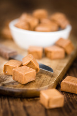 Portion of Caramel pieces on wooden background (selective focus)