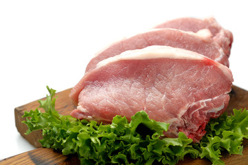 raw pork steaks, lettuce on a cutting board