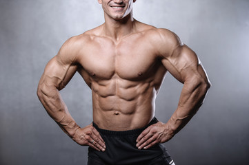 Fototapeta na wymiar beautiful fitness male model posing in studio on white grey back
