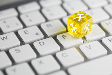 Gelb farbener / gelber Würfel mit Hammer und Schraubenschlüssel auf Tastatur