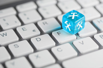Blau Türkis farbener / blauer türkiser Würfel mit Hammer und Schraubenschlüssel auf Tastatur