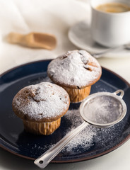 Breakfast with muffins with powdered sugar on dark blue plate.