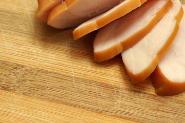 Sliced chicken ham on wooden background