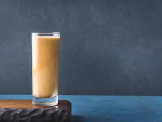 Long glass with coffee drink and cream on dark blue and black textured background