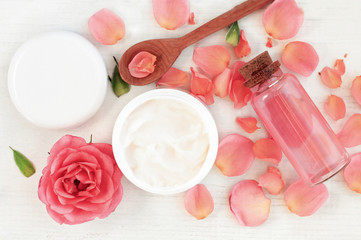 Skincare beauty treatment plant-based products with wink rose petals. Jar of body moisturizer, attar bottle toning lotion, top view homemade cosmetic ingredients.
