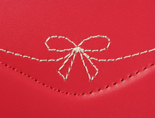 white embroidery in the shape of a bow on pink leather