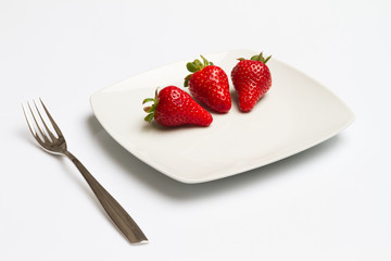 Strawberry in plate with fork isolated