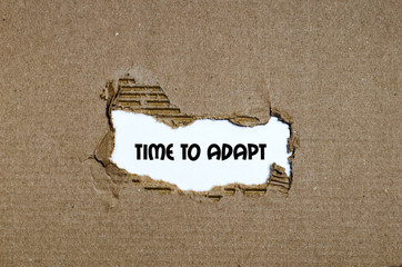 The word time to adapt appearing behind torn paper